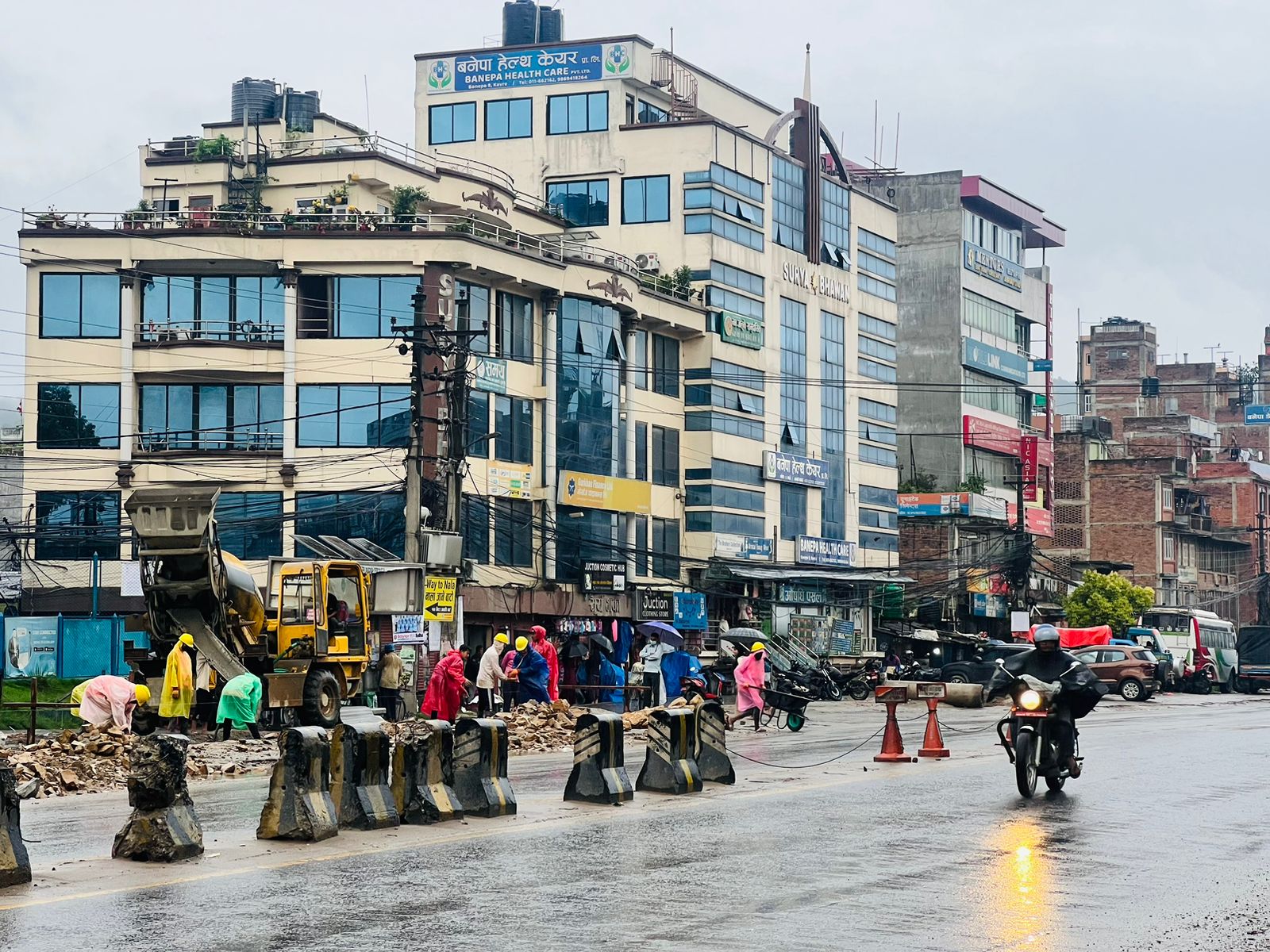 अरनिको राजमार्ग अन्तरगत बनेपा खण्डमा झरिमा पनि काम गर्दै मजदुरहरू ।